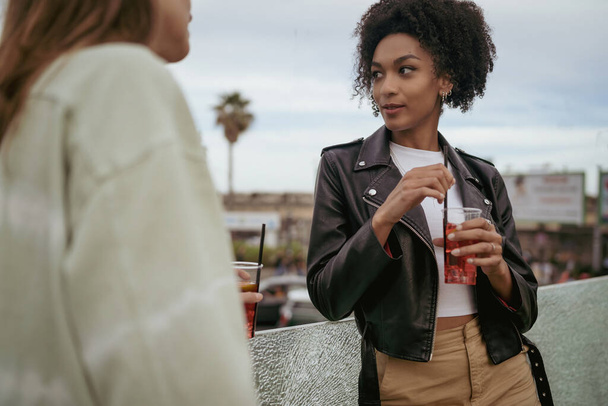 Jen ženy multiraciální nejlepší přátelé na ulici popíjet koktejly a mluvit spolu stojí venku ve městě.  - Fotografie, Obrázek