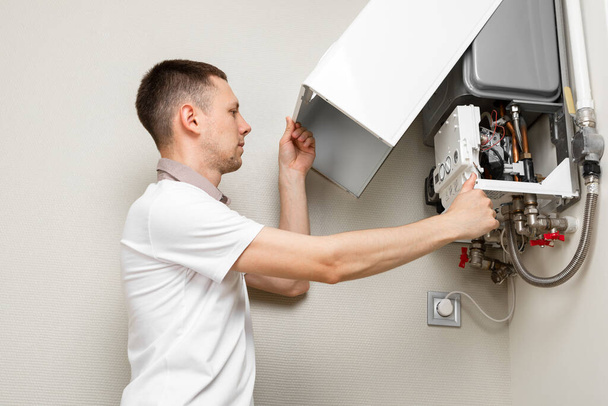 Plumber attaches Trying To Fix the Problem with the Residential Heating Equipment. Repair of a gas boiler - Fotoğraf, Görsel