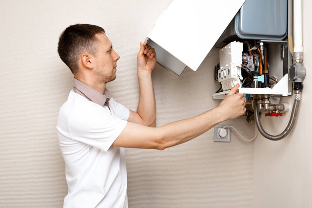 Plumber attaches Trying To Fix the Problem with the Residential Heating Equipment. Repair of a gas boiler - Zdjęcie, obraz