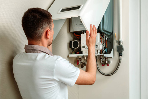 Plumber attaches Trying To Fix the Problem with the Residential Heating Equipment. Repair of a gas boiler - Foto, Imagem