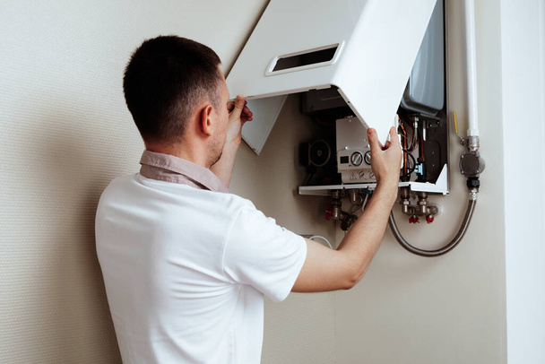 Plumber attaches Trying To Fix the Problem with the Residential Heating Equipment. Repair of a gas boiler - Foto, Bild