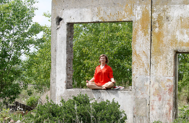 Красива жінка сидить в позі лотоса в старій будівлі
 - Фото, зображення
