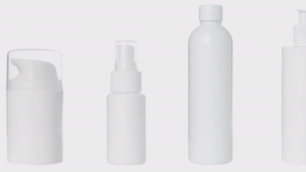4K video, bottiglie vuote di plastica bianca per cosmetici, crema, lozione, siero, farmaci su sfondo bianco. - Filmati, video