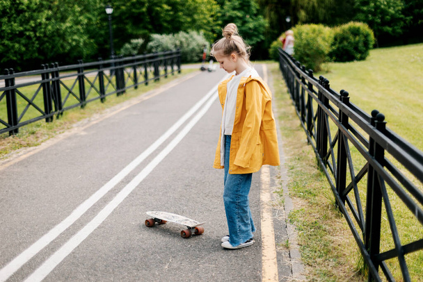 Joyeux adolescent fille apprendre à monter un skateboard dans le parc de la ville. - Photo, image