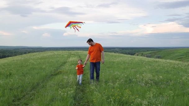 Happy family, daughter and dad raise a kite into the sky. Family weekend play outdoors. Child and dad play together with kites against the sky in the park. The concept of healthy children and parents. - Foto, Imagen