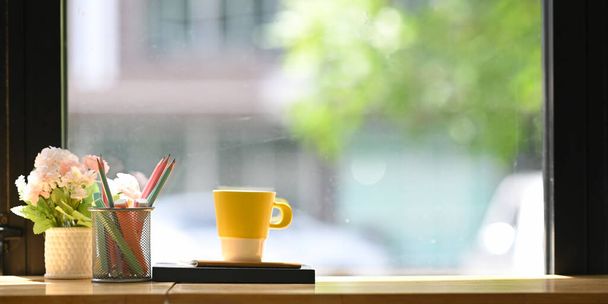 чашка кави на блокнотах з олівцями та квітами на дерев'яній стійці
  - Фото, зображення
