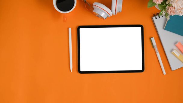 espacio de trabajo naranja con tableta y equipo de computadora de pantalla blanca en blanco. - Foto, Imagen