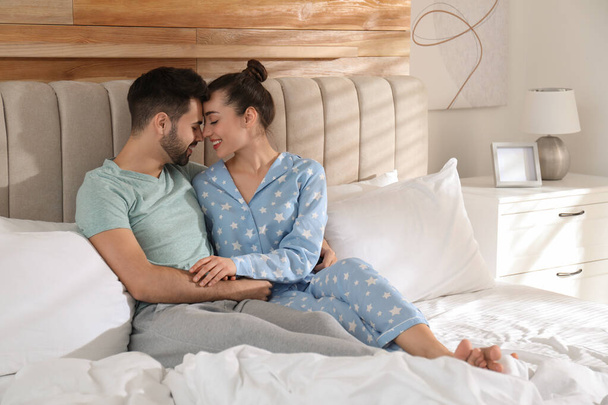 Happy couple in pajamas on bed at home - Foto, imagen