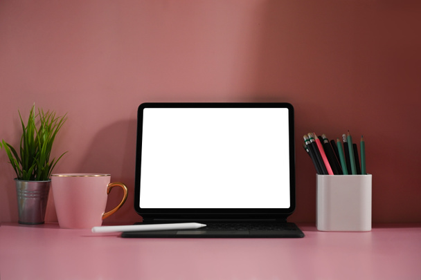 Computer-Tablet mit weißem leeren Bildschirm auf rosa Arbeitsfläche - Foto, Bild
