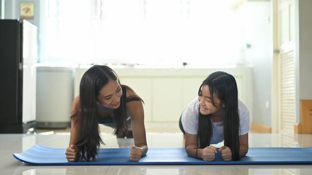 Asiática madre e hija están haciendo planking ejercicio juntos en casa. - Foto, imagen