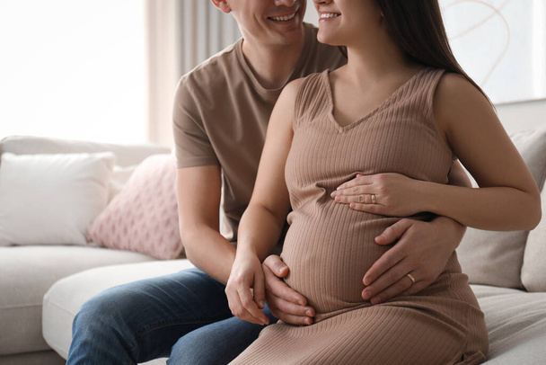 Man touching his pregnant wife's belly at home, closeup - Fotó, kép