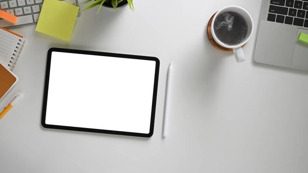 Η πάνω όψη της ψηφιακής ταμπλέτας με λευκή κενή οθόνη στο χώρο εργασίας  - Φωτογραφία, εικόνα