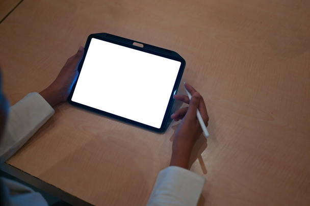 Bir kadının en üst görüntüsü, tahta masada beyaz beyaz ekranlı bir tablet kullanmasıdır.. - Fotoğraf, Görsel