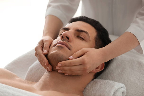 Man receiving facial massage in beauty salon - Foto, imagen