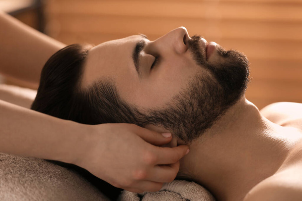 Young man receiving facial massage in beauty salon, closeup - Fotó, kép