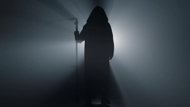 Silhouette grim reaper standing indoors. Death with scythe spotlight background. - Footage, Video