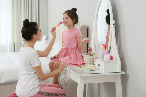 Young mother and her daughter spending time together in bedroom - Foto, Imagem