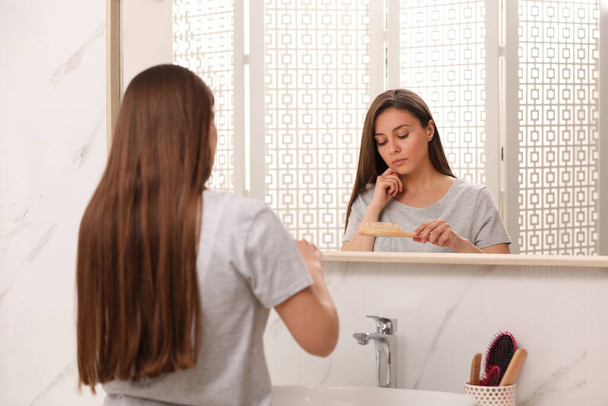 Young woman with hair loss problem near mirror in bathroom - Foto, immagini