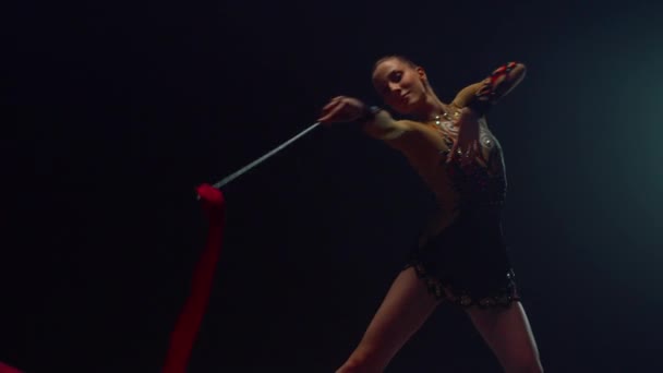 Lány tornász, aki szalagokkal táncol idebent. Ritmikus gimnasztikát végző sportoló. - Felvétel, videó