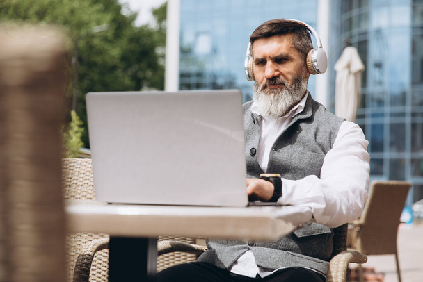 Starší muž stylový muž s šedým vousem tráví čas venku v notebooku. - Fotografie, Obrázek