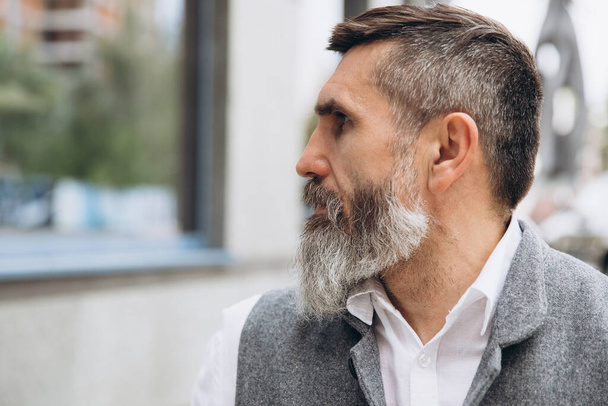 Gri sakallı ve vahşi bir adamın portresi. Temiz kentsel alanlarda vakit geçiriyor.. - Fotoğraf, Görsel