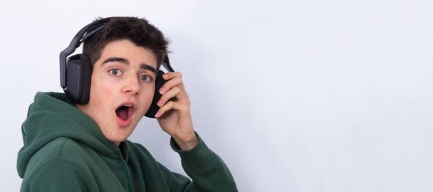 adolescente com fones de ouvido e expressão surpreso isolado em branco - Foto, Imagem