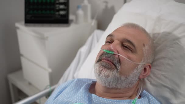 An elderly patient wakes up coming out of a coma. Open your eyes while lying on a bed in a hospital connected In the Hospital Sick Male Patient Sleeps on the Bed, . - Video
