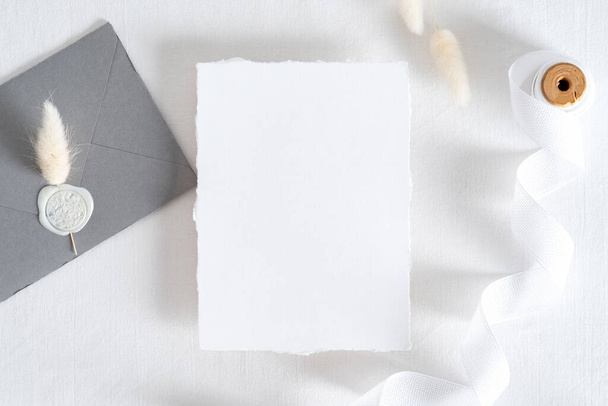 Flatlay wedding invitation card, grey envelope with seal wax stamp, dried flowers on pastel white background. Wedding stationery set top view. - Valokuva, kuva