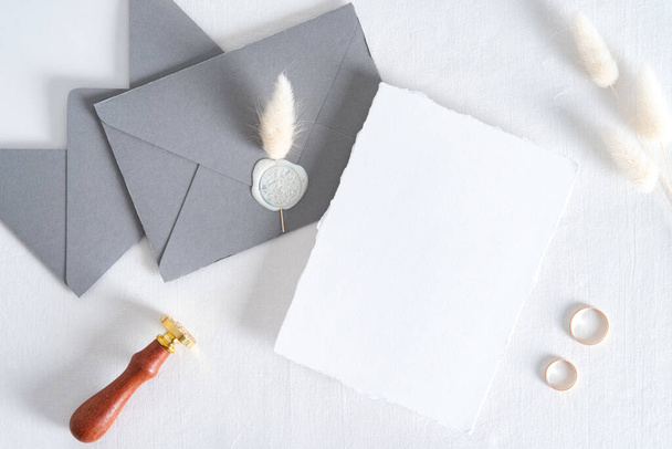Wedding invitation card mockup, grey envelopes, rings on white background. Flat lay, top view. Minimal style. - 写真・画像