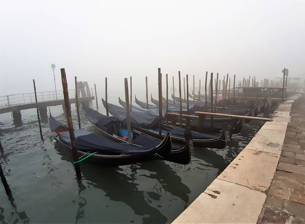 Венеція (Італія) 27 січня 2020 року, гондоли пришвартовані до стовпів пірса в туманний день. - Фото, зображення