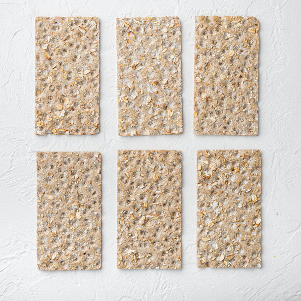 Set de pan crujiente ligero de dieta de grano, formato cuadrado, sobre fondo de mesa de piedra blanca, vista superior plano, con espacio de copia para texto - Foto, imagen