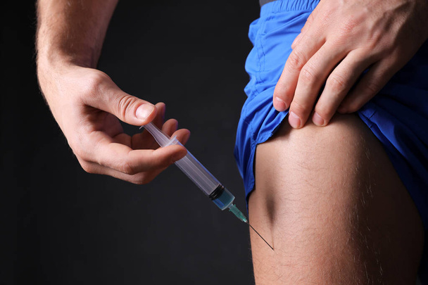 Man injecting himself on black background, closeup. Doping concept - Φωτογραφία, εικόνα