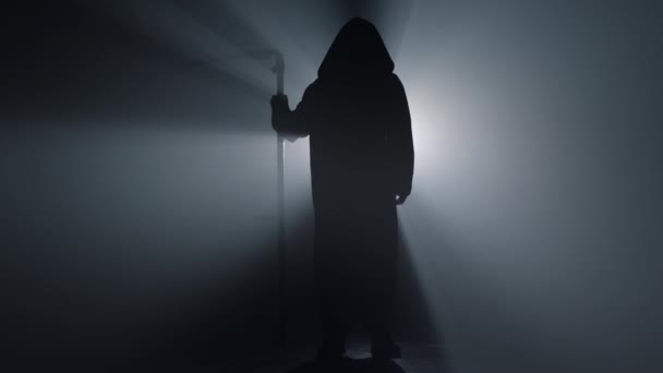 Silhouette τρομακτικό scytheman στέκεται σε σκοτεινό φόντο. Θλιβερός θεριστής μέσα. - Πλάνα, βίντεο