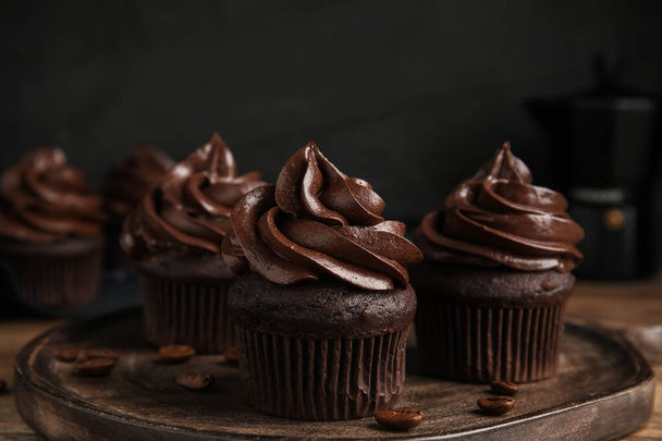 Delicious chocolate cupcakes with cream on wooden table - Foto, imagen