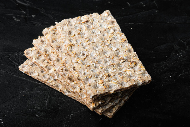 Ropogós ropogós ropogós kenyér Egészséges snack készlet, fekete sötét kő asztal háttér - Fotó, kép