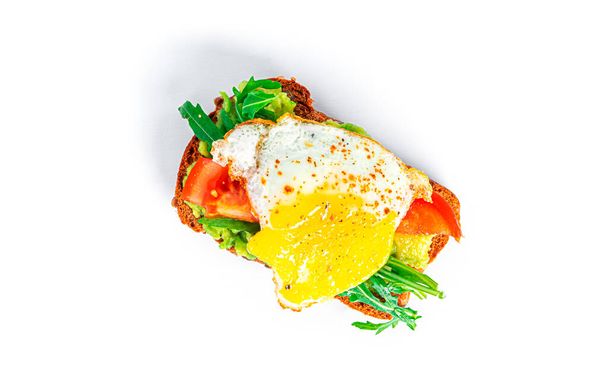 Rye bread sandwich with guacamole, arugula, tomatoes and quail egg isolated on a white background. Bruschetta with avocado. Healthy breakfast. - Foto, Imagem