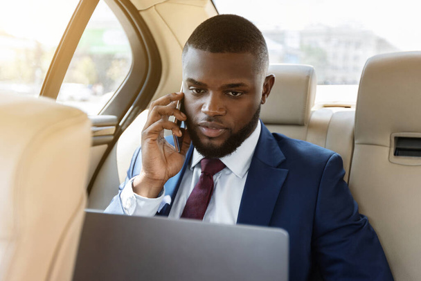 Businessman working on laptop, using smartphone while going to airport - Photo, Image