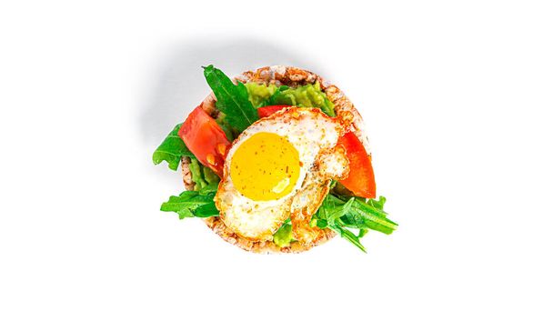 Crispbread sandwich with guacamole, arugula, tomatoes and quail egg isolated on a white background. Bruschetta with avocado. Healthy breakfast. - Foto, afbeelding