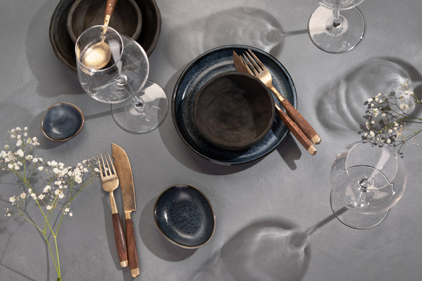 Table setting with a black and blue plates on gray background. Minimalism concept. Top view - Zdjęcie, obraz