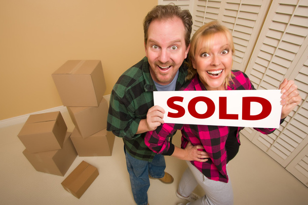 Goofy пара холдинг продается знак в комнате в окружении картонных коробок
. - Фото, изображение