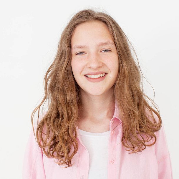 Natural young girl with happy smile, turn head at camera and looking cheerful, standing against white background in pink shirt. Portrait of fun teen student Studio Shot - Foto, imagen