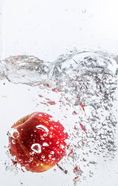 Splash of water with red apple and white background. - Photo, Image