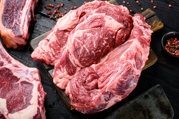 Tlusté hovězí žebírko. Mramorované bio maso ribeye steak set, na tmavém dřevěném pozadí - Fotografie, Obrázek