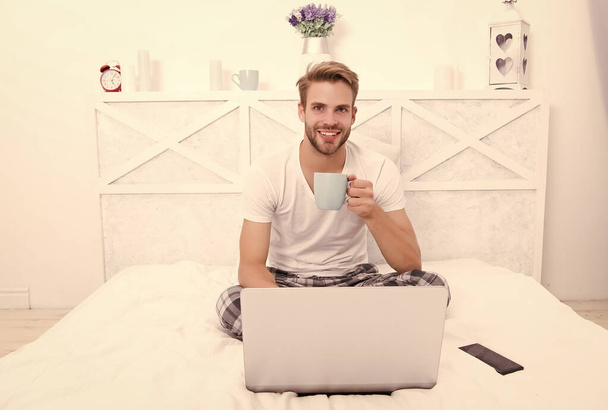 Happy man with laptop hold cup to stay hydrated being sick in bed at home with COVID-19, hydration - Valokuva, kuva