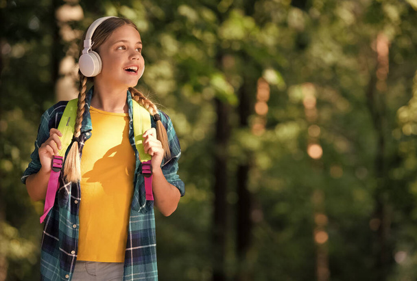 English as second language. Happy child listen to headphones natural outdoors. Language learning courses. Foreign language school. New technology. Private teaching. Summer vacation, copy space - Fotografie, Obrázek