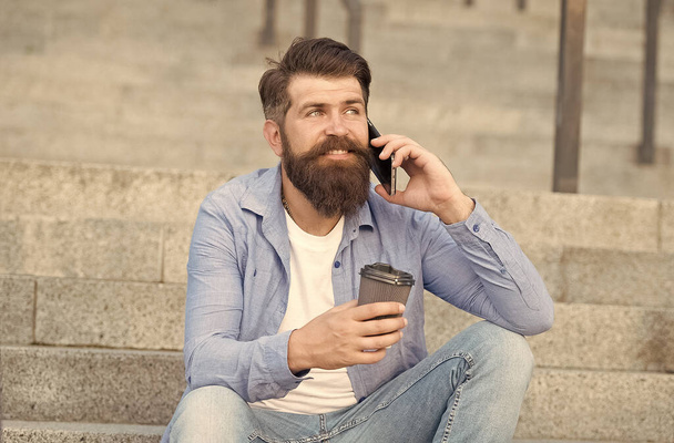 Pleasant conversation. Real connect. Drink coffee while talking. Modern urban life. Bearded man phone conversation. Mobile conversation. Coffee break. Personal communication. Calling friend - Fotó, kép