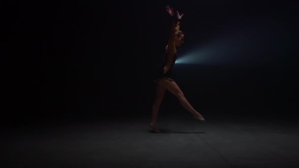 Atletische vrouw doet handstand in donkere studio. Flexibele gymnastiektraining binnen - Video