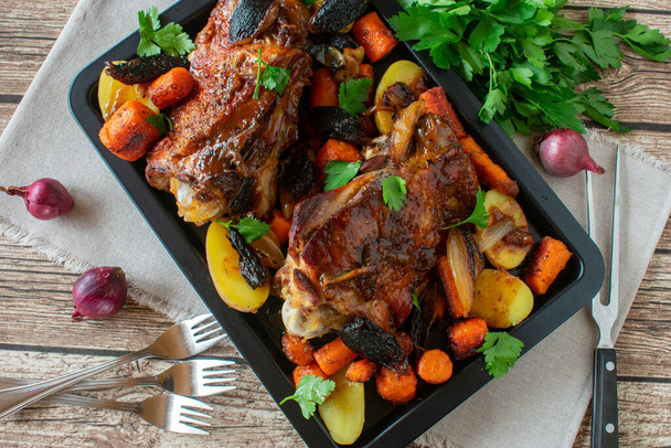 Roast turkey legs with potatoes and vegetables served on baking sheet on rustic table background with overhead view - Photo, Image