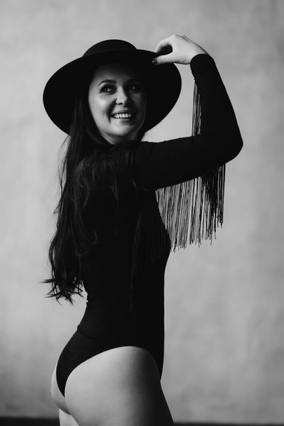 happy and beautiful woman with long dark hair in a black bodysuit and hat.  - Fotografie, Obrázek