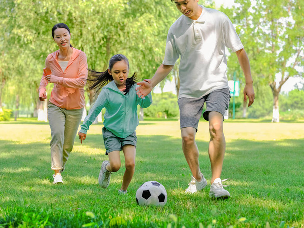 Happy family of three playing football in the park - Photo, Image
